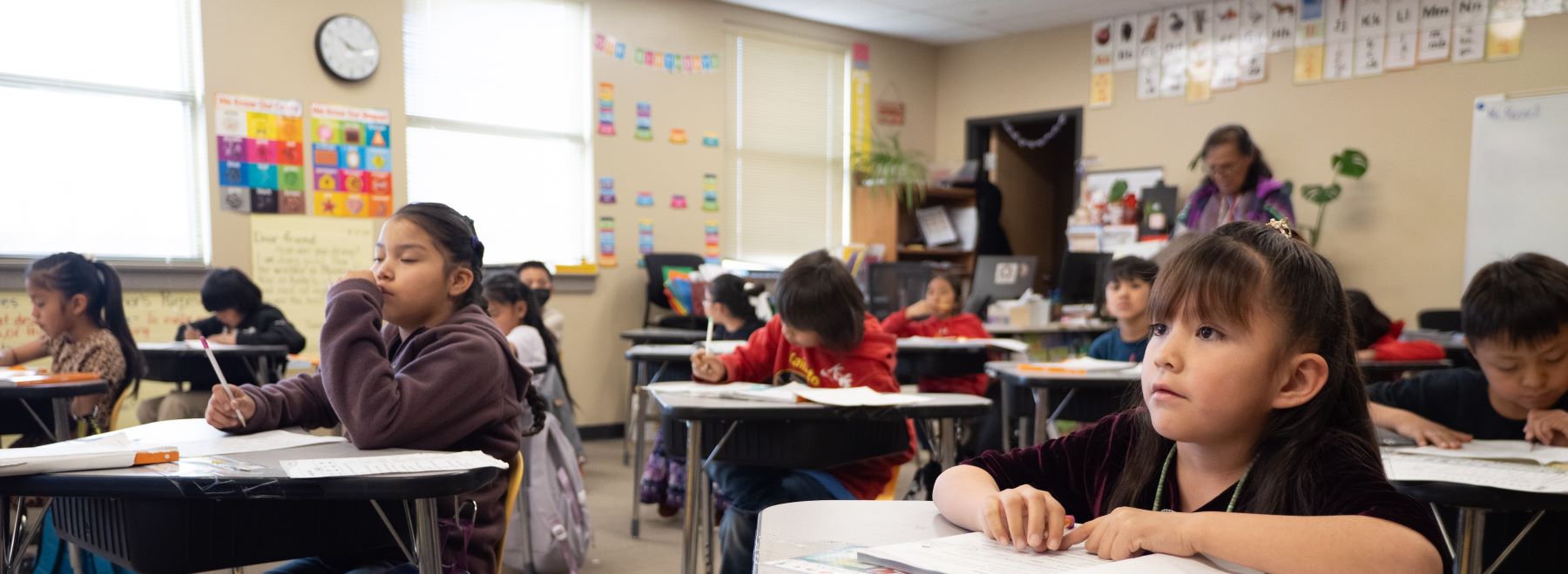 Students sitting at desks in a classroom, focused on their papers during a school class activity.