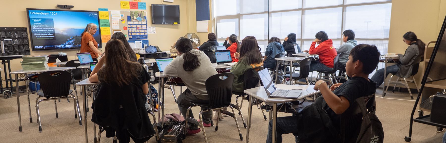 A classroom filled with students at desks, each using laptops for their school class activities.